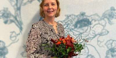 Mirja Mustasilta kädessään eläkkeelle jäämisen kunniaksi annettu kaunis kukkakimppu